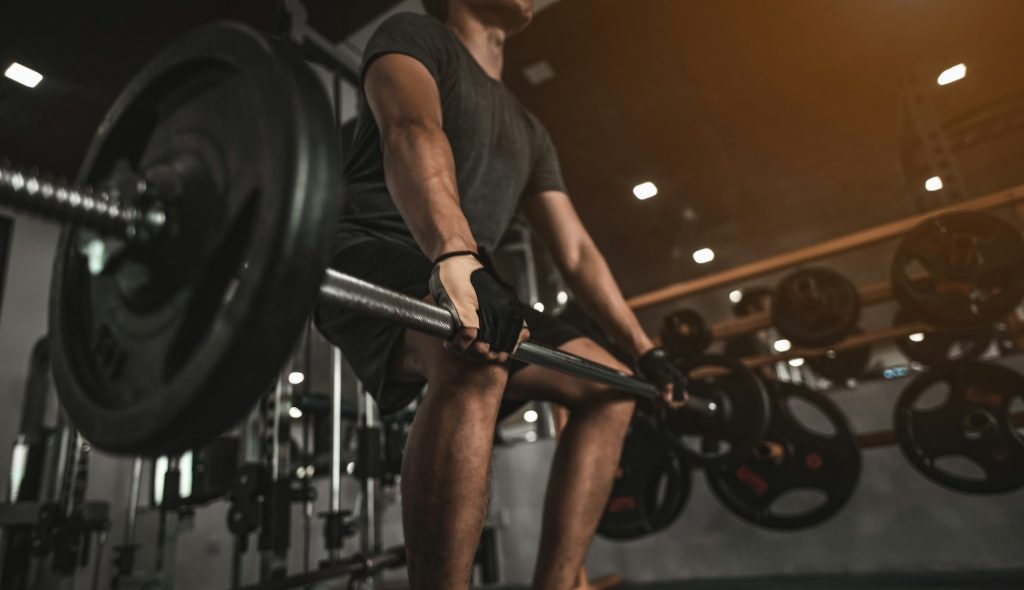 A side view of a young bodybuilder exercising in the gym, ready to lift weights, lift weights