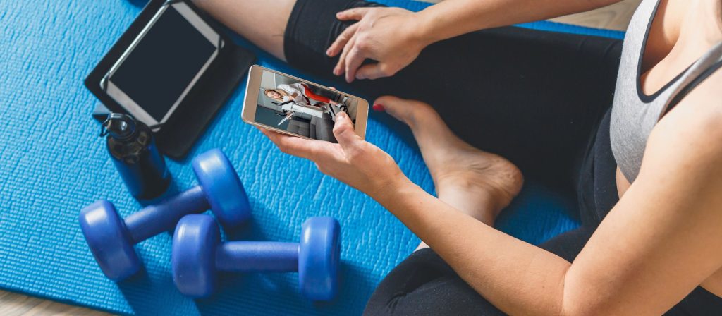 Fitness at home, remote training with virtual instructor. Woman in sportswear sitting on the floor