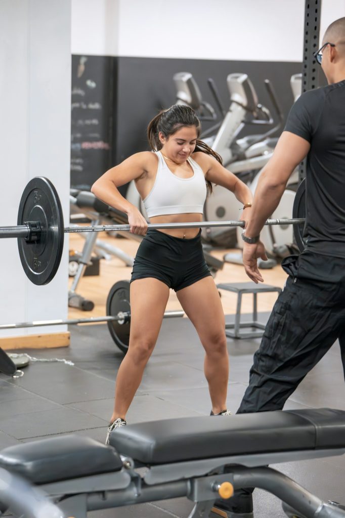 Woman lifting weights at gym with trainer